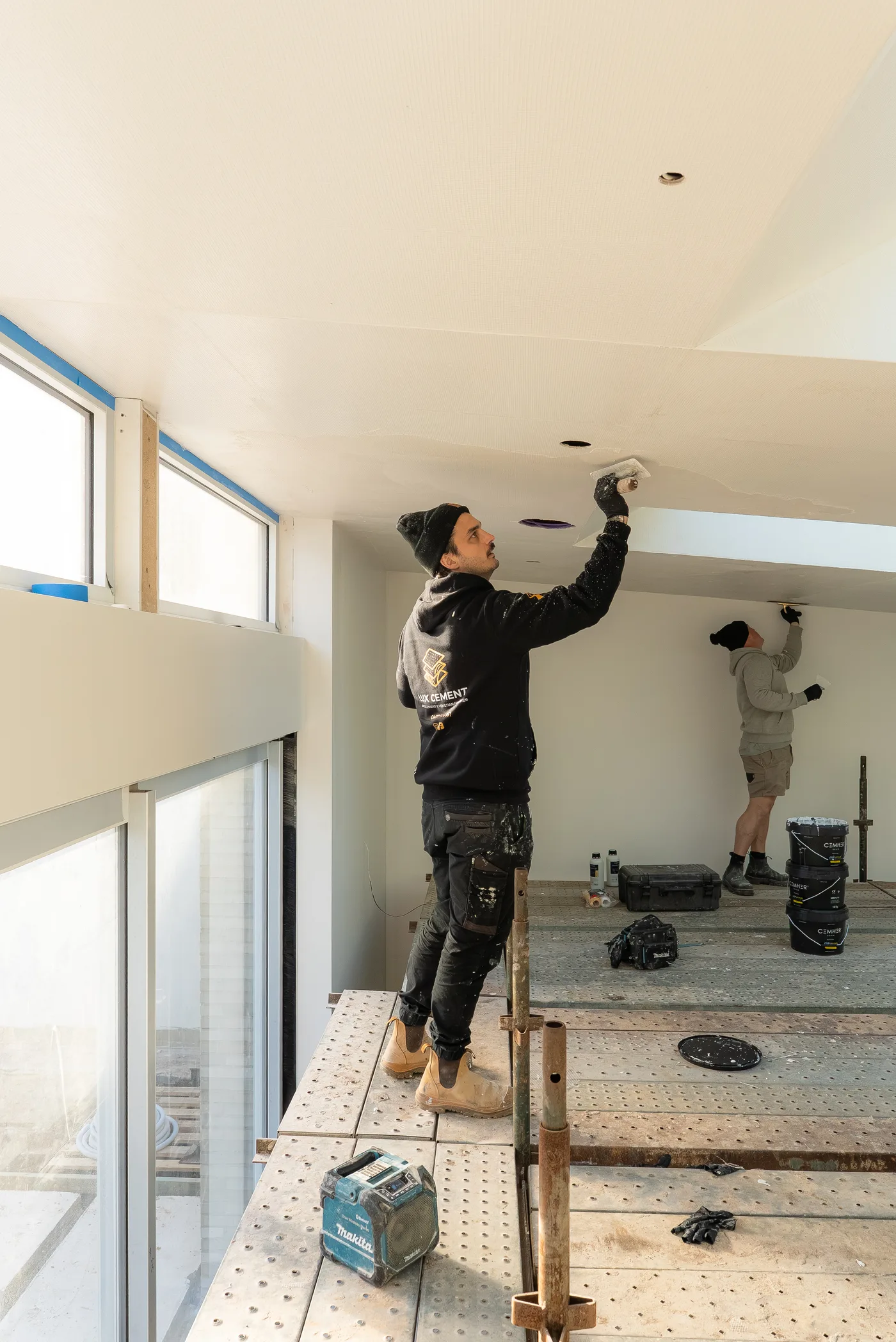 Lux Cement team hand-applying finish to a ceiling from scaffold